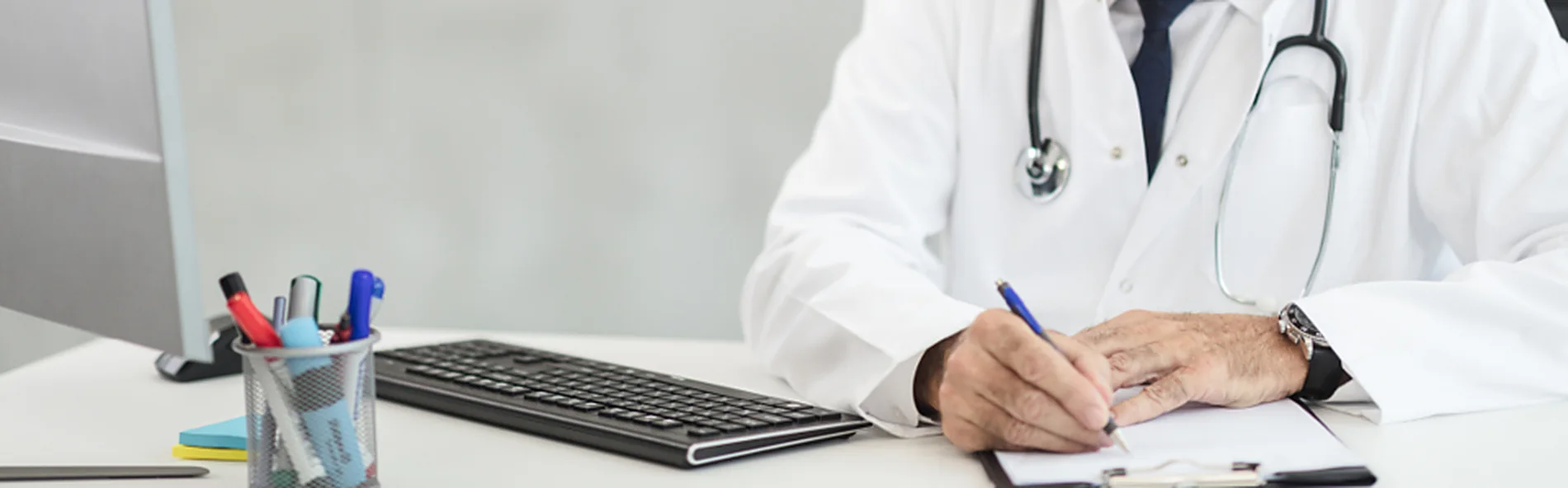 A clinician writing patient notes at a desk